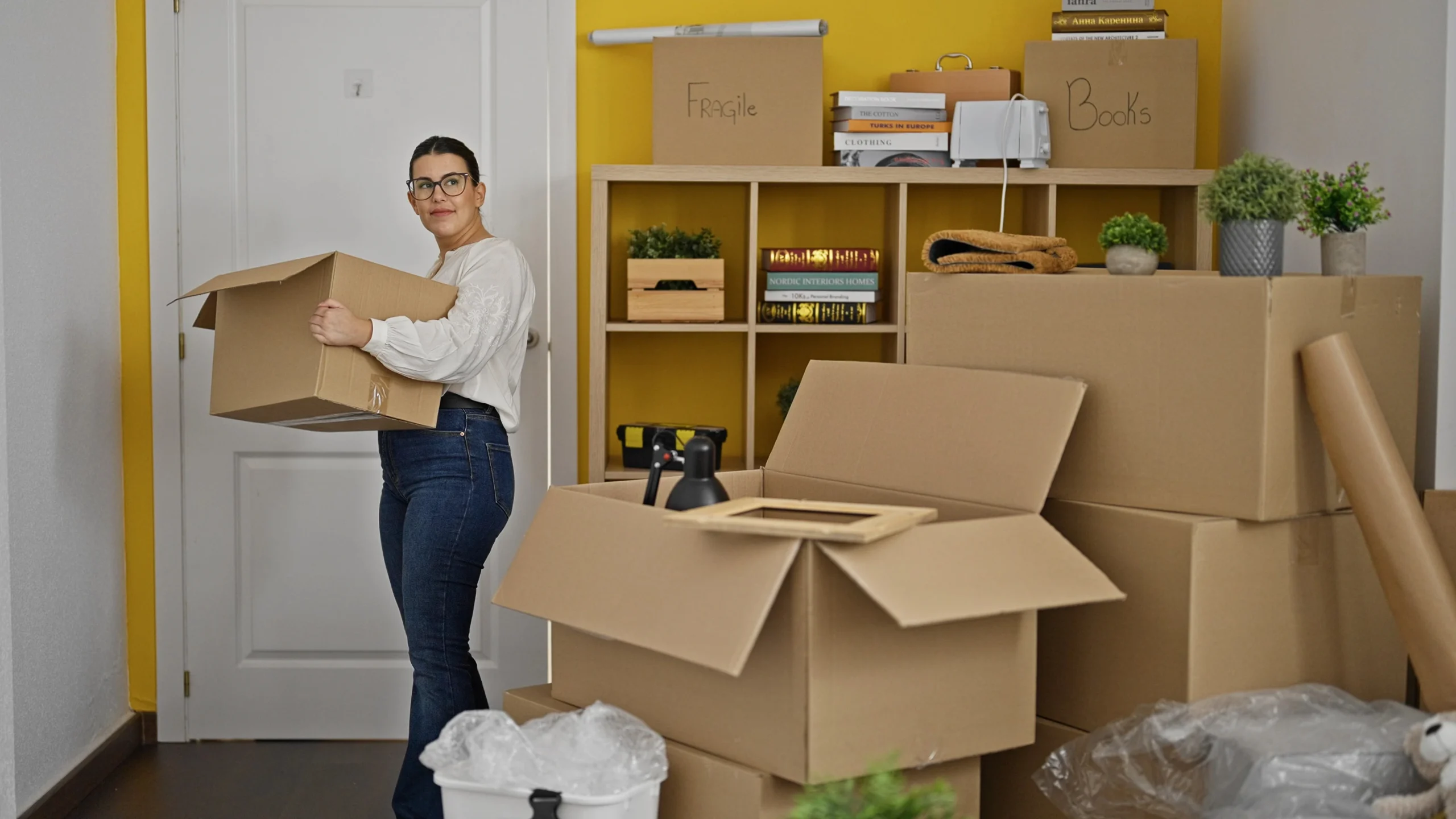 Smiling Woman Holding A Moving Box In A Cosy Lounge, Professional Packers Near Me